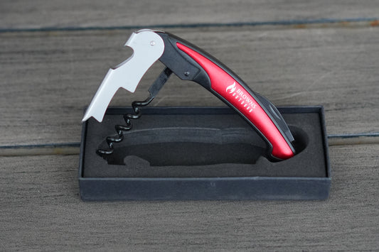 Wine opener with red handle and corkscrew in a black box on a wooden surface