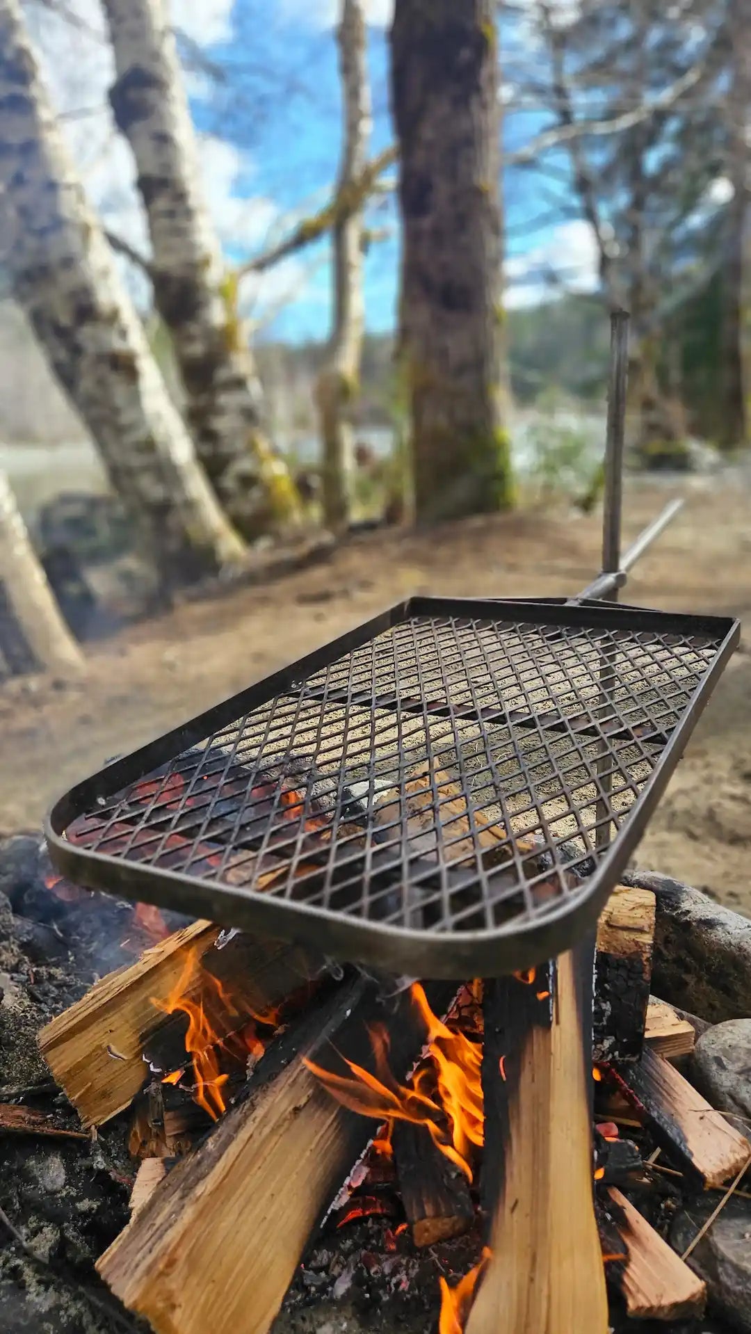 Anvil grill over fire at a campsite 