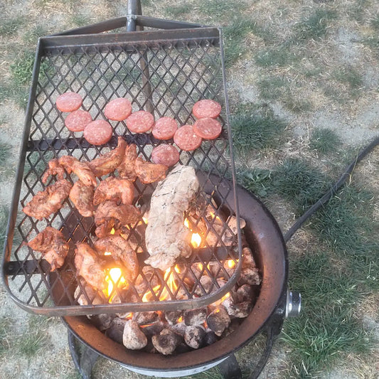 Sausage and chicken on the anvil grill over propane fire